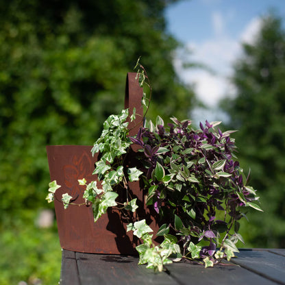 Rustic metal planter with handle, cut-out floral pattern, natural rusty finish